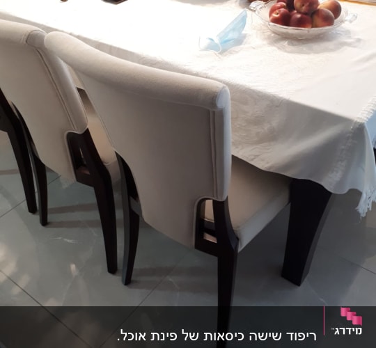 כיסאות מרופדים ליד שולחן עם מפה לבנה